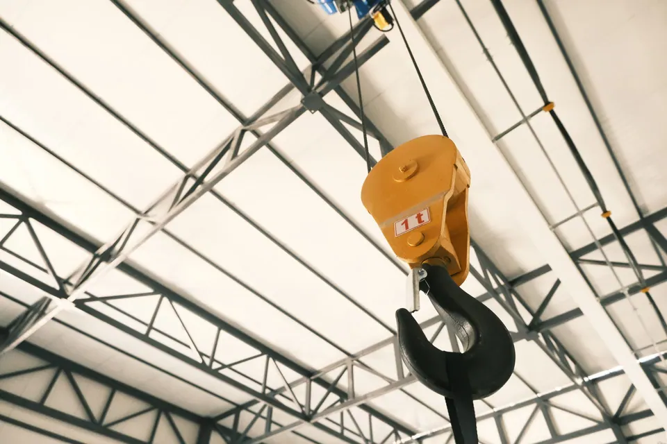 Overhead crane hook under the roof of an industrial building