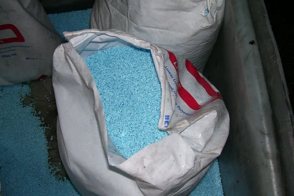 Blue plastic pellets in an open bulk bag